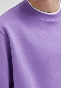 Sweatshirt violet avec un col rond et un col côtelé. Tissu doux en mélange de coton et coupe décontractée avec des détails de couture minimalistes.