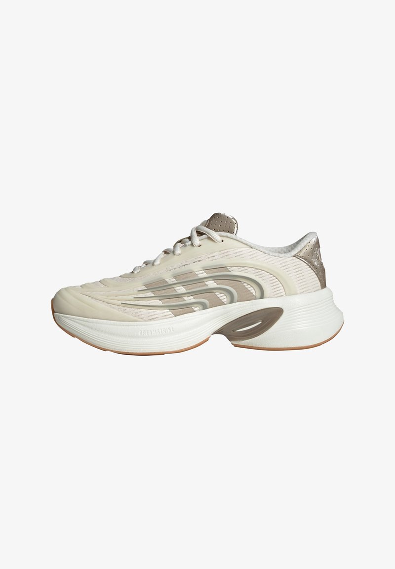 Light beige athletic shoe with textured upper, silver accents, and a cushioned sole. Features a rounded toe and perforated heel for breathability.