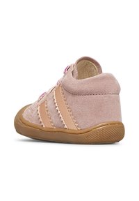 Chaussure en daim rose clair avec une semelle en caoutchouc texturé, dotée de trois rayures ton sur ton, d'un système de laçage et de détails texturés à l'arrière.