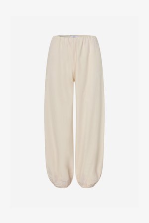 Pantalon beige coupe ample avec taille élastique et ourlets élastiqués, conçu pour un usage décontracté.