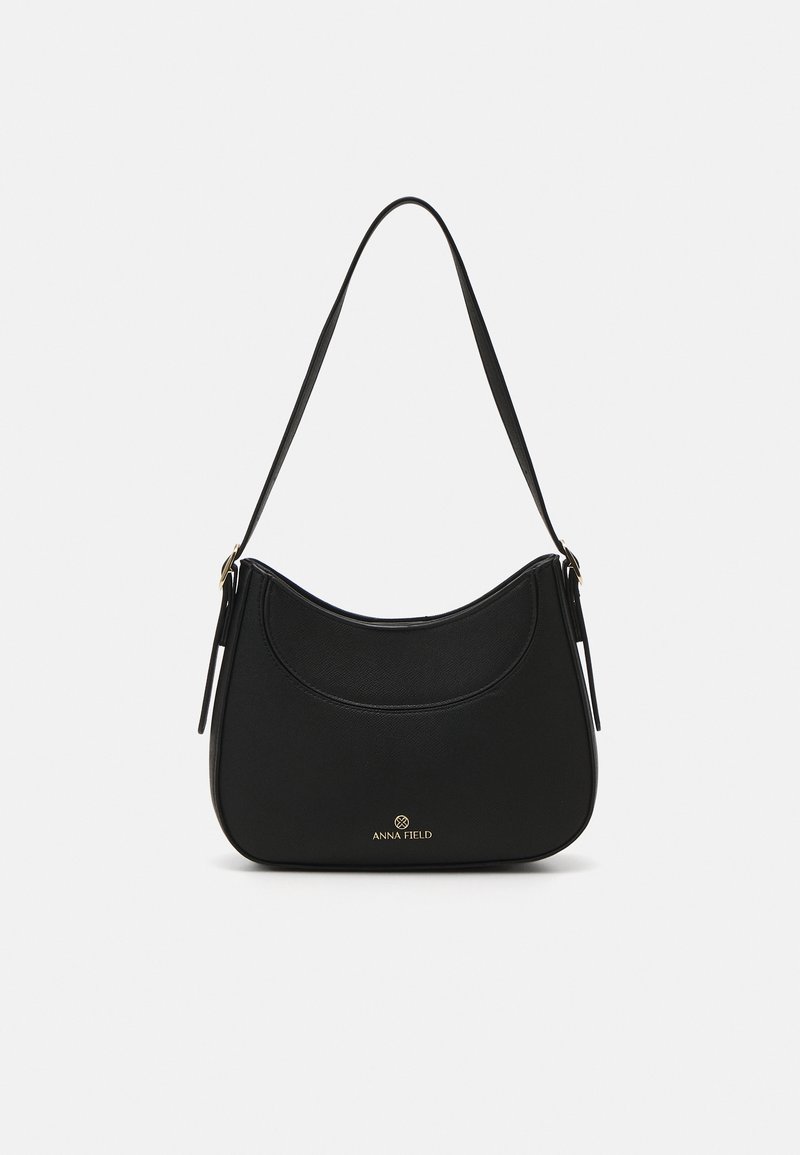 Musta kuun muotoinen olkalaukku, jossa on yksi hihna ja pieni kultainen "ANNA FIELD" -logo etuosassa.