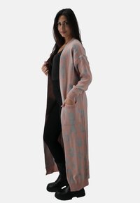 Cardigan lungo rosa lavorato a maglia con stampa leopardata turchese, dotato di polsini a costine, tasche e un design aperto davanti.