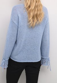 Ljusblå stickad tröja med lös passform, med intrikata spetsdetaljer vid ärmarna och ribbade muddar.