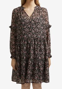 Vestido floral de tela negra transparente con flores rosas y azules. Presenta un escote en V, mangas largas con puños con volantes y una falda con volantes.