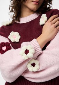 Μπορντό και ροζ πλεκτό πουλόβερ με κεντητές ανθισμένες λεπτομέρειες· διαθέτει ριμπ μανσέτες και απαλή υφή· λουλούδια σε κρεμ και βουργουνδί.