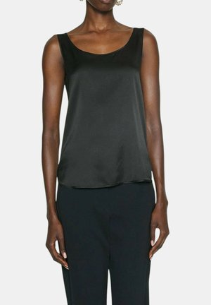 Top senza maniche di raso nero con scollatura a barca, texture liscia e vestibilità rilassata, abbinato a pantaloni neri.