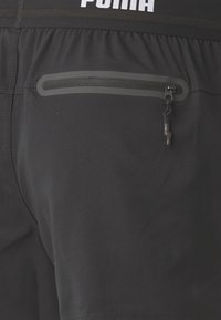 Svarte treningsshorts med en glatt tekstur, elastisk midjebånd med logo og en glidelåslomme med en trekkflik.