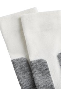 Bílé a šedé pruhované ponožky z texturované tkaniny, se základním šedým pruhem na kotníku pro větší kontrast.