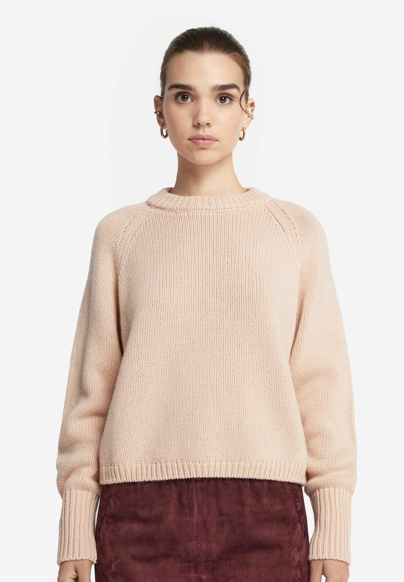 Helles rosa Strickpullover mit rundem Ausschnitt, gerippten Bündchen und Saum, der eine weiche Textur und einen lockeren Schnitt aufweist.