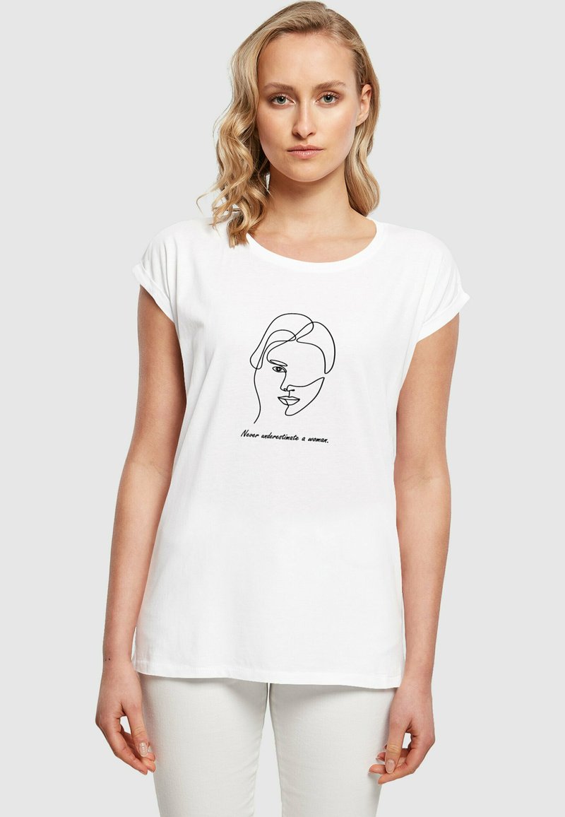 Hvid bomulds T-shirt med rullede ærmer, der har en sort linjetegning af et ansigt og teksten "Undervurder aldrig en kvinde."