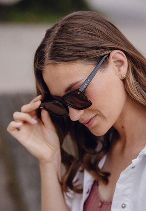 Černé obdélníkové sluneční brýle mají tmavé čočky a jemné zlaté logo na stranách. Rám má lesklý povrch.