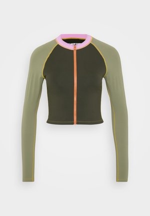 Gekürzte Jacke in olivgrün mit langen Ärmeln, kontrastierendem pinkem Kragen, orangefarbenem Reißverschluss und gelben Nähten. Glattes, tailliertes Design.