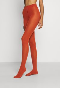 Collants opaques orange avec un design sans couture, taille haute et texture lisse. S'ajuste étroitement aux jambes, longueur cheville sans motifs.