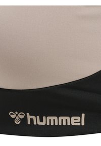 Beige en zwart stof met het Hummel-logo, met een gestileerde bij en de merknaam in kleine letters.