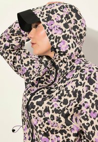 Leopardmönstrad jacka i nyanser av beige, svart och lila, med huva, dragkedjestängning och justerbara snörningsdetaljer.