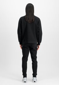 Svart, langermet sweatshirt og matchende bukser, laget av mykt materiale, med en avslappet passform. Har rund hals og ribbestrikkede mansjetter.