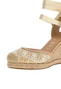 Wedge de esparto beige con parte superior tejida y con patrón, interior de tela suave y correas de satén en el tobillo. Base de plataforma de yute natural.