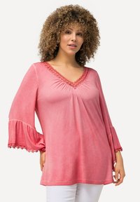 Top rosa a scollo a V con dettagli arricciati, bordi in pizzo sulle maniche a campana e una vestibilità comoda. Tessuto morbido, con leggera variazione di colore.