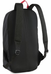 Sort rygsæk med justerbare stropper, mesh-struktur på bagsiden, flad design og livligt rød accent på top håndtaget. Minimalistisk look.
