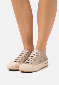 Beige Wildleder-Sneaker mit goldenen Ösen und hellen Gummisohlen, featuring einer abgerundeten Zehenpartie und lässigem Design.