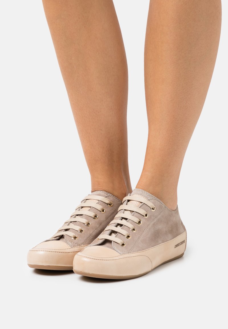 Beige Wildleder-Sneaker mit goldenen Ösen und hellen Gummisohlen, featuring einer abgerundeten Zehenpartie und lässigem Design.