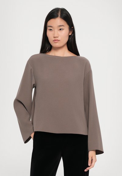 Brown, long-sleeve top with a boat neck design, made from a smooth fabric. Features a relaxed fit and slightly flared sleeves.