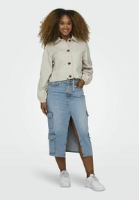 Bežna kratka jakna z gumbom in elastičnimi manšetami, v kombinaciji z svetlo modrim denim midi krilom z sprednjim razporkom in cargo žepi.