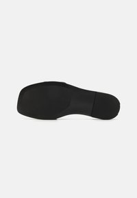 Black shoe sole with a smooth rectangular shape, textured heel, and flat bottom. Features minimal branding on the side.