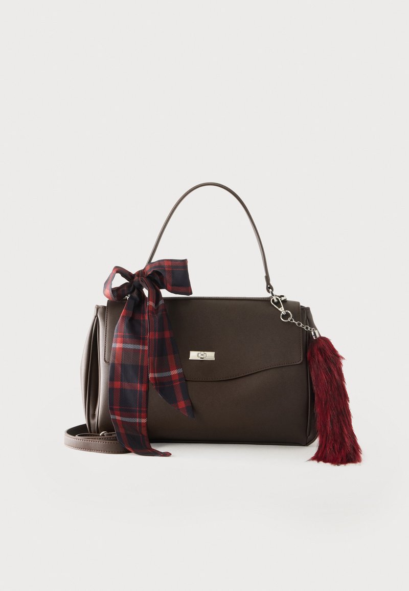 Sac à main marron foncé avec une anse supérieure, un nœud à carreaux rouge à gauche et un porte-clés rouge duveteux à droite sur un fond uni.