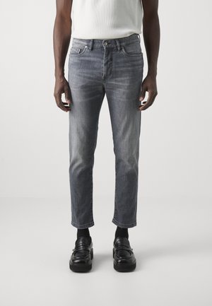 Jean en denim gris avec une finition légèrement délavée, coupe droite et design à cinq poches, accompagnés de mocassins noirs.