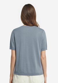 Kortärmad topp i skifferblått i ett lätt material. Har rund halsringning, avslappnad passform och ribbade ärmslut med en slät textur.