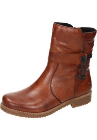 Bottine en cuir marron avec un bout arrondi, design ample, sangle décorative avec un nœud, et semelle en caoutchouc texturé.