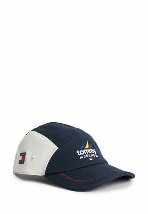 Marineblauwe en witte Tommy Jeans pet met geborduurd logo en kleurrijk zeilbootontwerp aan de voorkant, weergegeven op een witte achtergrond.