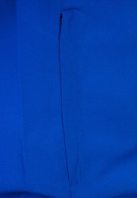 Blå tyg med en slät yta, med en sydd vertikal söm. Materialet är lätt och matt, utan synliga mönster eller metallföremål.