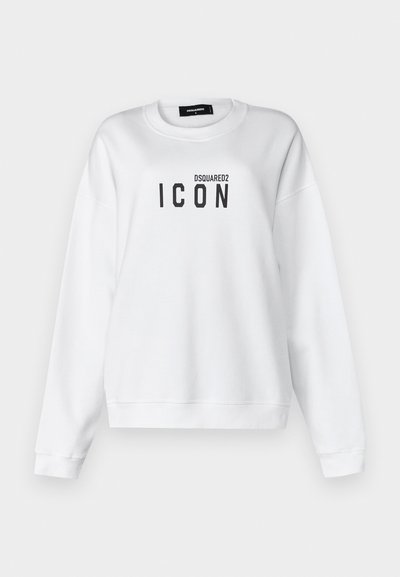 Valge puuvillasegusest kangast t-särk ümmarguse kaeluse, rippuvate õlgade ja musta "ICON" logoga esiosas. Puhtad jooned.