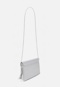 Bolso sintético gris claro con textura suave, diseño de solapa, correa de cadena y detalle de borla. Forma rectangular, aspecto minimalista.