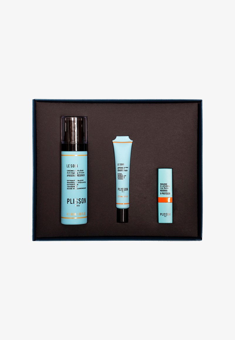 Three skincare products in a blue and orange color scheme, packaged in a dark box. Includes a cream, lip balm, and serum.
