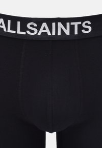 Schwarze Boxershorts aus weichem Stoff, mit einem elastischen Bund, der "ALLSAINTS" in kontrastierendem weißen Schriftzug zeigt.