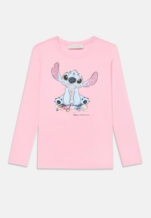 Camisa de manga larga rosa hecha de algodón. Presenta un gráfico de un personaje azul con orejas grandes y ojos negros, rodeado de flores.