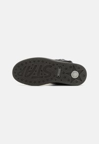 Semelle extérieure en caoutchouc noir avec grip texturé, présentant des étoiles en relief, un logo "STARP" et un détail logo circulaire. Design durable et à motifs.