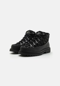 Schwarze Wanderschuhe mit einer strukturierten Oberseite, die ein Muster aufweist, robusten Gummisohlen, Metallösen und Schnürsenkeln für eine sichere Passform.