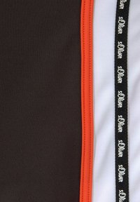 Black fabric section with an orange seam, white fabric section adjacent, and a black ribbon with the text "s.Oliver" in a repeating pattern.