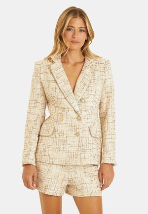 Blazer beige in tweed con un design doppiopetto, ampi risvolti e due tasche anteriori. Tessuto testurizzato con sottili fili dorati.