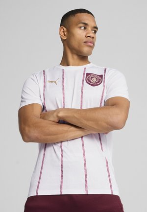 Hvid sports skjorte med maroon lodrette striber, featuring en rund hals, korte ærmer, guld Puma-logo og et maroon klubmærke på brystet.