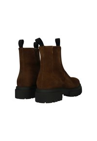 Botas de tobillo de ante marrón con una suela de goma negra gruesa, cremallera lateral y tiradores en los talones para facilitar el uso. Textura suave.