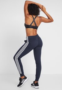 Svart sportbh med korsad baksida, tillsammans med marinblå joggers med vita sidostreck. Joggers har elastisk midja och mudd.