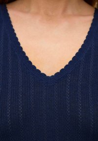 Top lavorato a maglia blu navy con scollatura a V ondulata, texture a coste verticali e piccoli motivi aperti in tutto il tessuto.