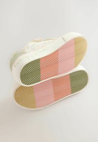 Farverige sneakers med teksturerede gummisåler i pink, grøn og beige, prydet med blomsterprint på overdelen og teksten "Alt er muligt."