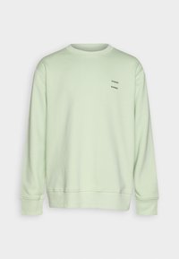 Sweatshirt vert clair en tissu doux, avec poignets côtelés et col rond. Petit logo texte noir sur le devant.