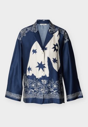 Marineblauw overhemd met witte bloemen- en sterrenpatronen, met een abstracte grote witte vorm in het midden en decoratieve kraag en manchetten.